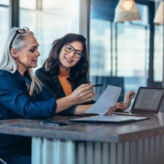 Two women analyzing documents at office